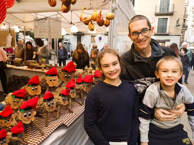 Family enjoying a festive market in Barcelona with charming stalls, perfect for a private tour of churros, hot chocolate, and games.