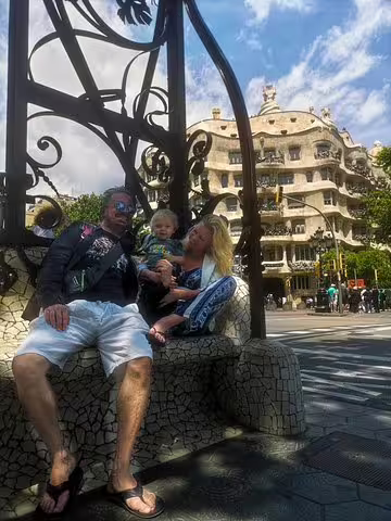 Family enjoying a sunny day near Casa Milà in Barcelona during a private tour featuring churros, hot chocolate, and games.
