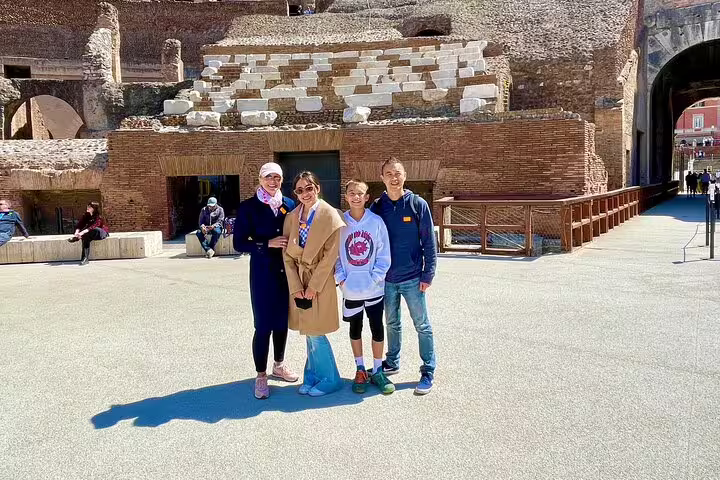 Happy family posing inside the Colosseum arena during a private VIP guided tour of ancient Rome and Vatican highlights
