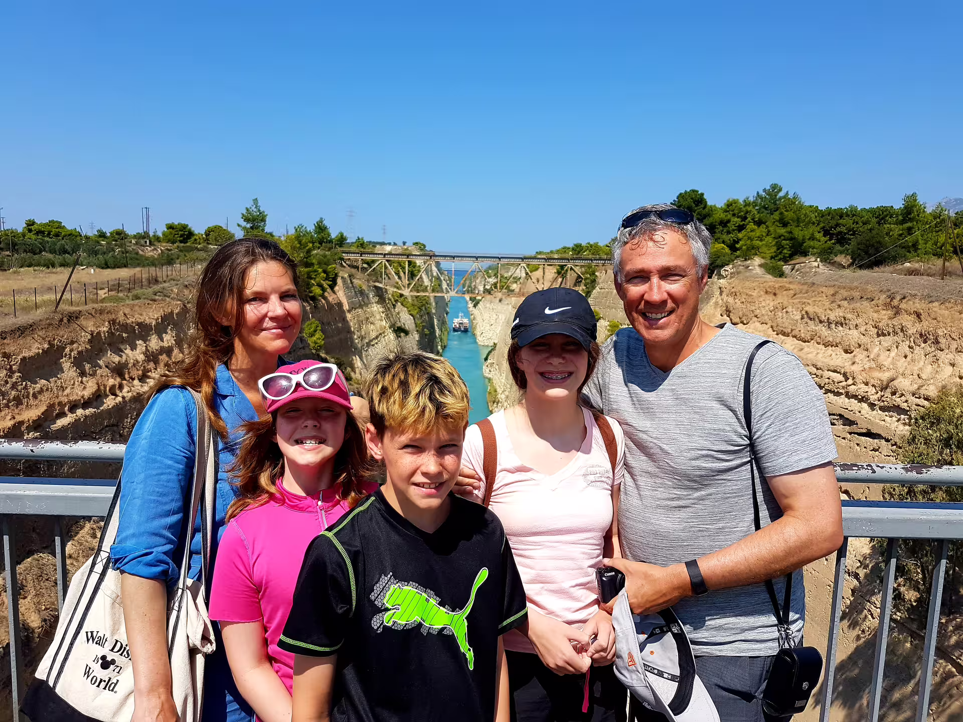 Family at the Corinth Isthmus Canal viewpoint on private day tour from Athens, canal and bridge behind