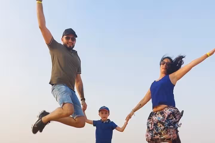 Family jumping on Ras Al Khaimah desert safari tour, fun photo stop after camel ride and dinner camp