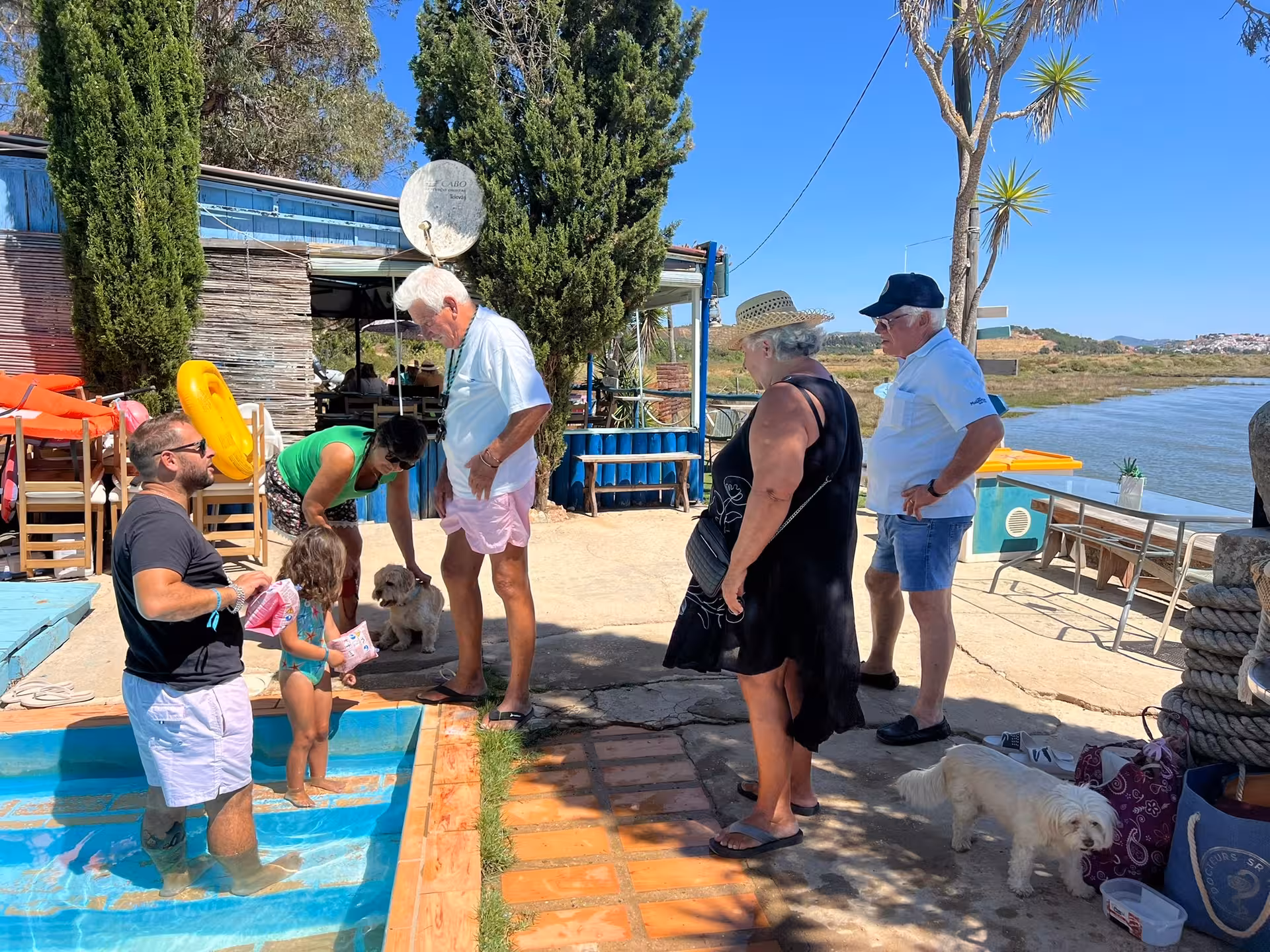 Multi-generational family and dogs enjoying a sunny riverside pier and poolside break on a customized Algarve boat charter