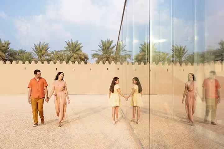 Family enjoying a reflective architectural marvel surrounded by palm trees on a garden city tour in Al Ain.