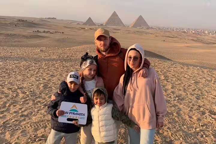Family photo on Giza Plateau with pyramids in the background during a private guided Giza Pyramids tour