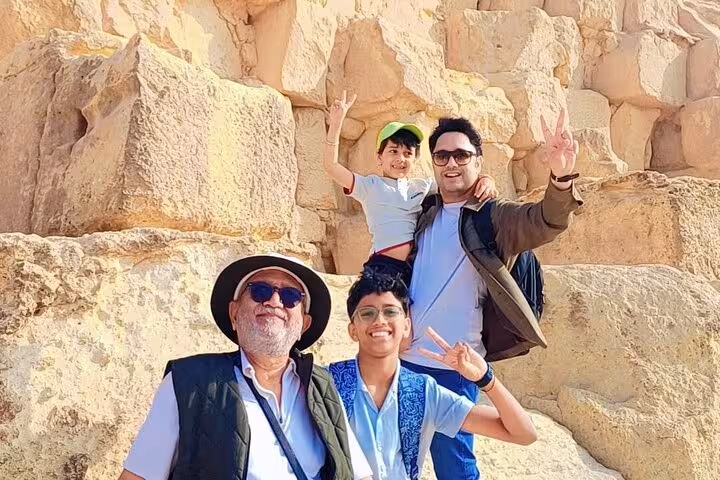 Family photo by the Great Pyramid stones in Giza, Egypt, private guided pyramids tour and desert experience
