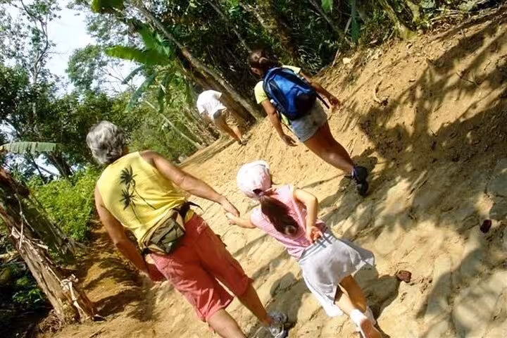 Family hiking along a scenic trail surrounded by lush greenery on the Gold Trail Adventure in Paraty.