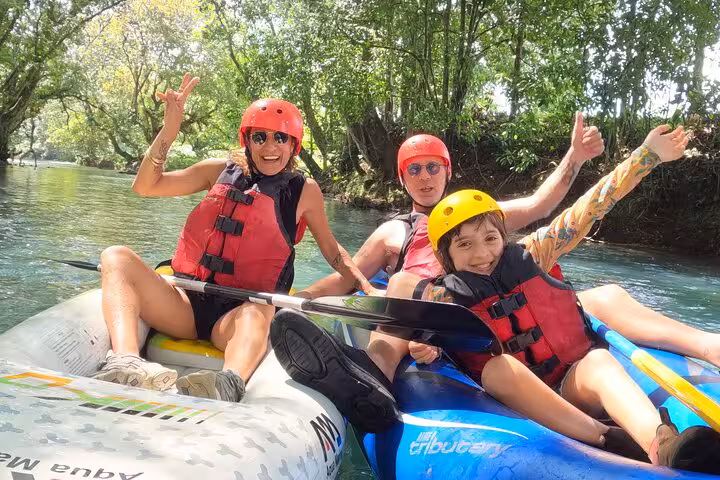 Excited family in kayaks celebrates their adventure on the picturesque and tranquil Río Celeste waters.
