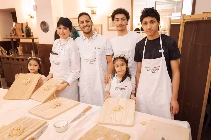 A family enjoys making fettuccine together at a pasta cooking class in Rome's Piazza Navona.
