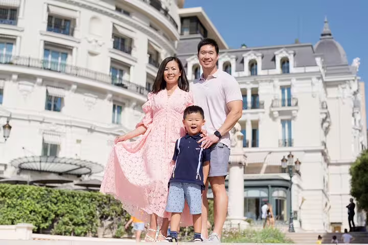 Happy family poses in front of a grand historic building in Nice, capturing memorable moments on a sunny day.