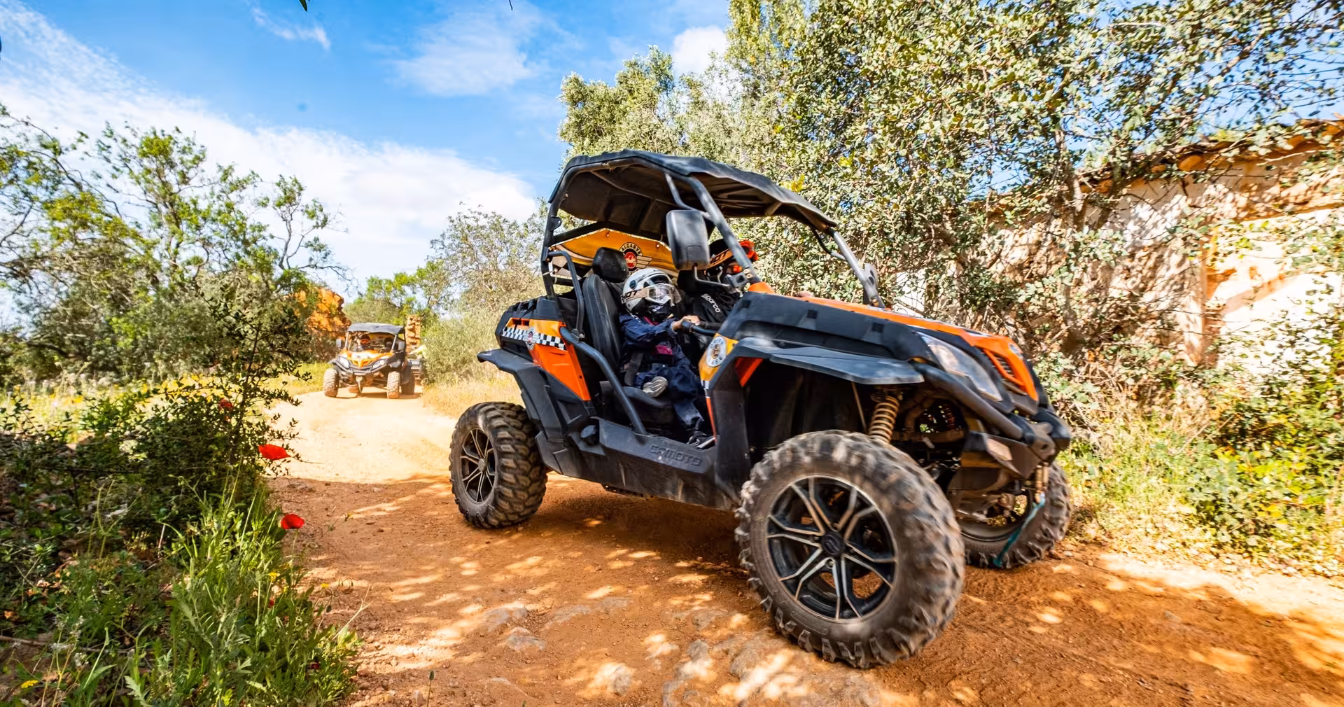 Family driving an orange off-road buggy on a dusty countryside trail during an adventurous Algarve buggy tour experience