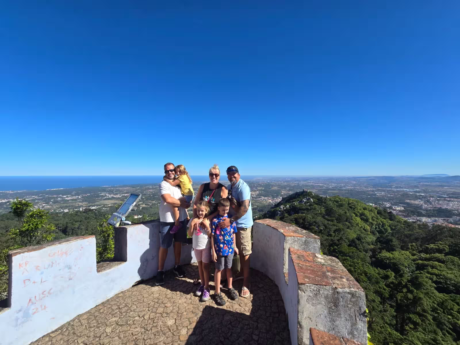 Family enjoying panoramic views from a scenic viewpoint in Sintra on a sunny day during a half-day private tour.