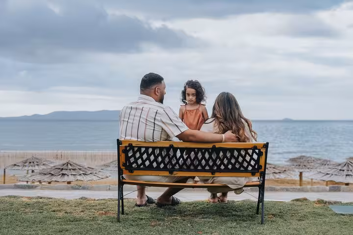 Family sitting on a bench overlooking Ammoudara beach, capturing a peaceful moment during their private photoshoot.