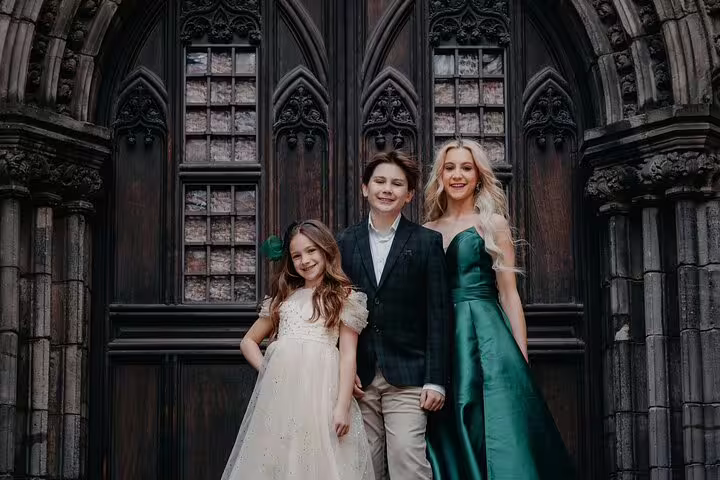 Family dressed elegantly posing in front of ornate medieval doors, capturing timeless elegance in Edinburgh.