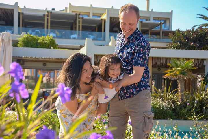 Happy family enjoying a playful moment amidst vibrant flowers during a private photoshoot in Heraklion.