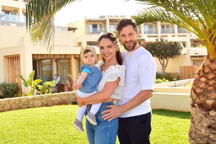 Happy family posing with their baby in a lush garden setting in Hersonissos, ideal for a memorable private photoshoot.