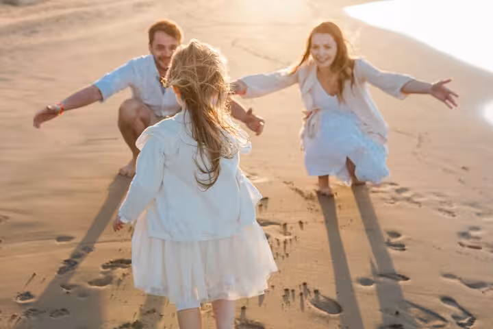 A family enjoying a playful moment on the sandy beach at Hersonissos Port during a private photoshoot experience.