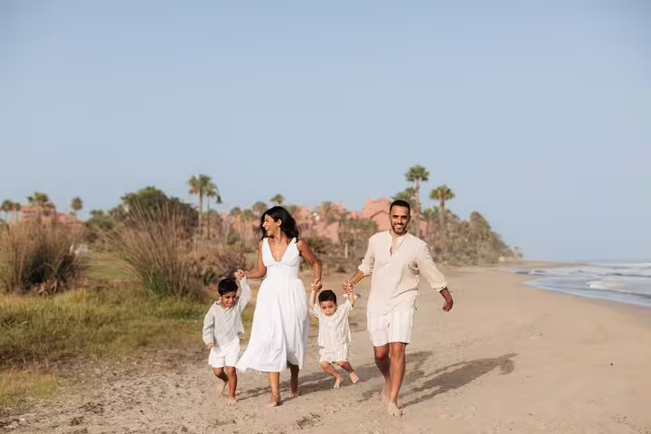 Family enjoying a playful moment on a sunny beach during a photoshoot in Marbella.
