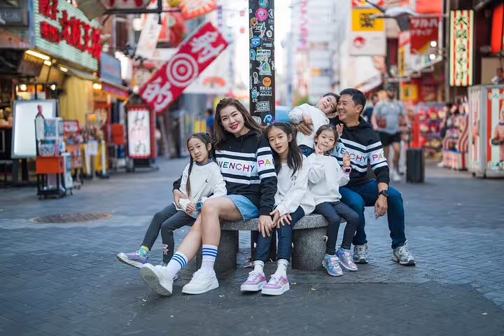 Family posing in lively Osaka street for a memorable private photoshoot experience with a professional photographer.