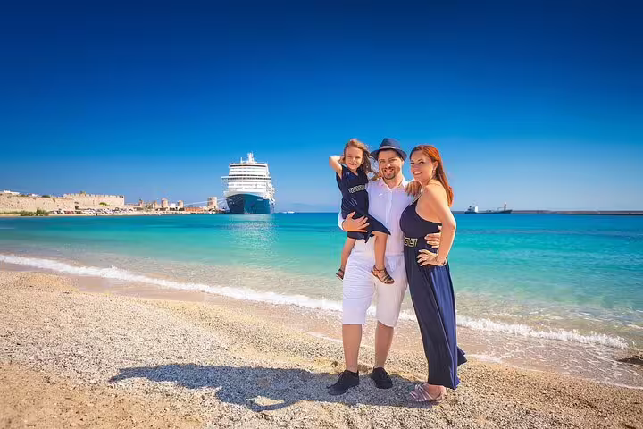 Family enjoying a private photoshoot on Rhodes beach with a cruise ship in the background under a clear blue sky.