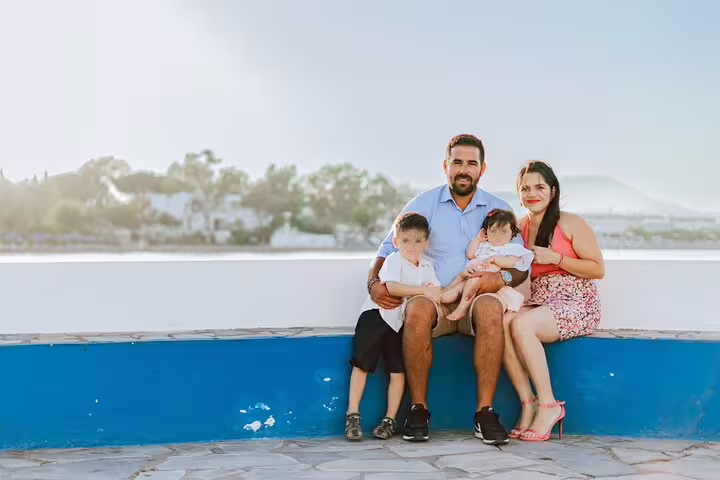 Happy family sitting on a bench by the sea in Rhodes, capturing precious moments with a professional photographer.