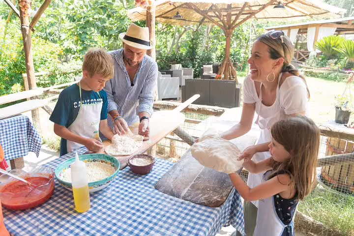 Family making pizzas outdoors at a local farm pizza school, with wine and limoncello tasting included