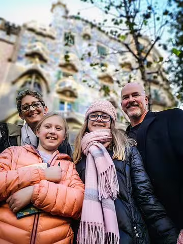Family enjoying a private tour in Barcelona, smiling in front of Casa Batlló, ready for churros, hot chocolate, and fun games.