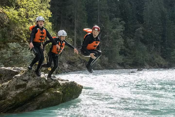 Three people in life vests jumping into Engadin river, showcasing family fun and adventure.
