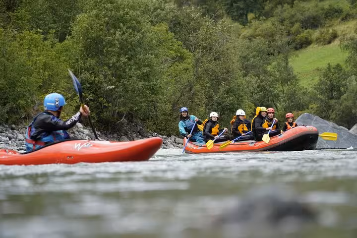 Group enjoying family rafting on the lively Engadin river, surrounded by lush greenery and scenic landscape.