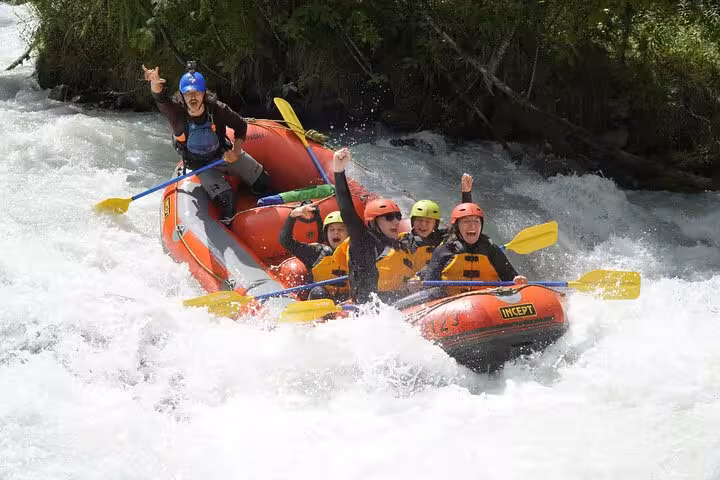 Family enjoying thrilling rafting adventure in Engadin's rapids, surrounded by lush greenery and whitewater excitement.
