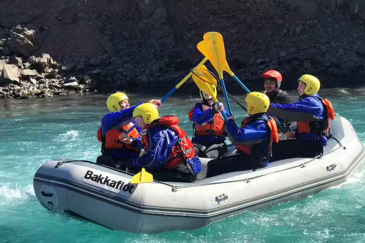 Family enjoying an exhilarating river rafting adventure, paddling together on clear blue waters, wearing safety gear and helmets.