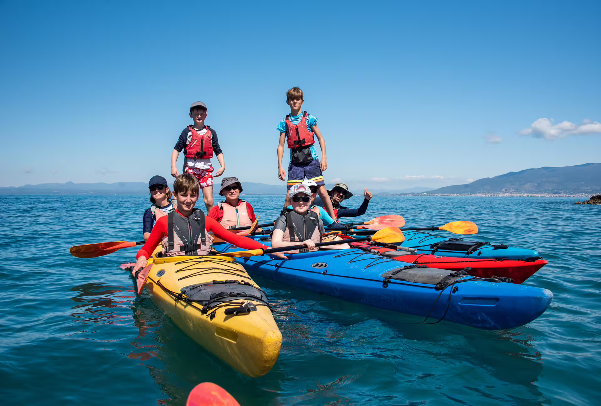 Family group in colorful kayaks on a guided sea kayaking adventure in Kalamata, Messinia, Greece