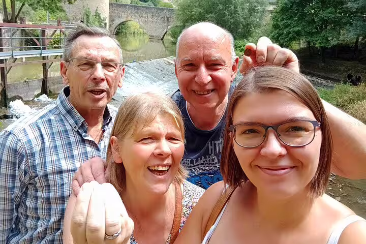 Family selfie by a river bridge during a Dijon e-scavenger hunt, enjoying a self-paced scavenger tour