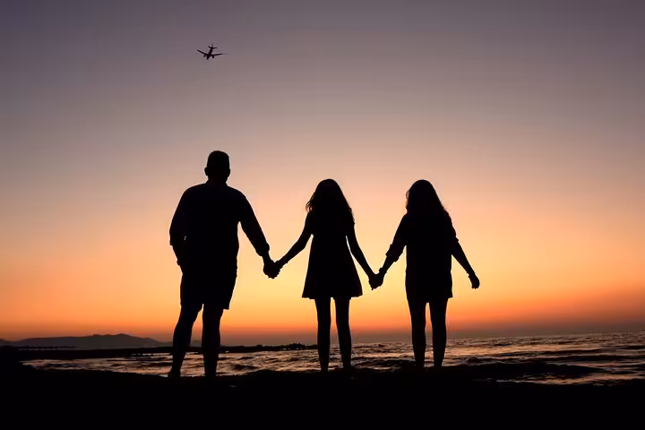 Family silhouette at sunset with plane in sky during private photoshoot at The Port of Hersonissos.
