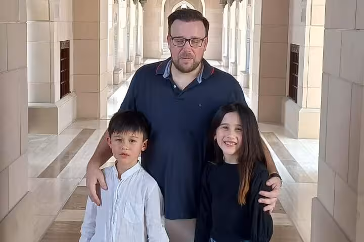 Family explores the elegant marble corridors of Sultan Qaboos Grand Mosque on a private Muscat sightseeing tour
