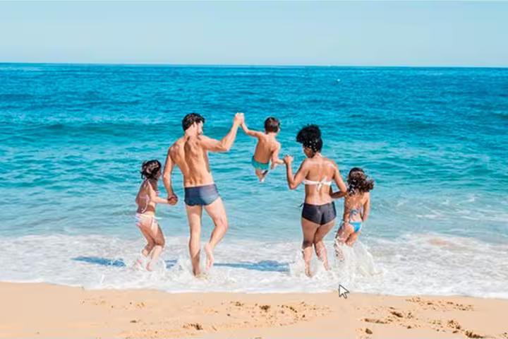 Family playing in Atlantic surf on Algarve beach, stop on private boat tour from Faro with swim time