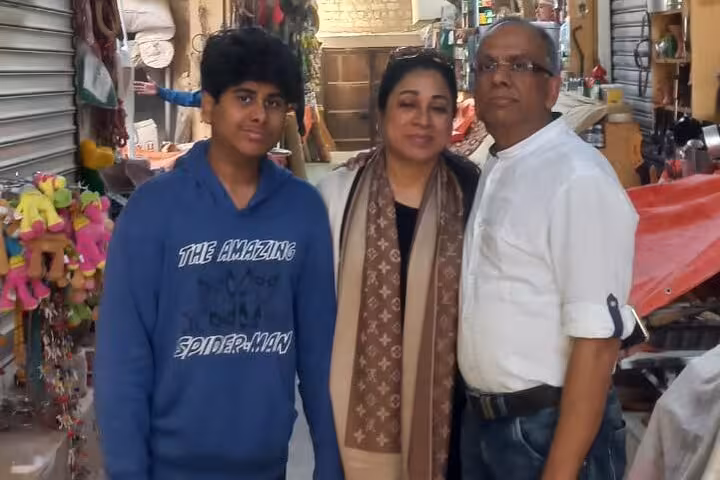 Family posing together inside a traditional Muscat souq, surrounded by colorful market stalls during a private sightseeing tour