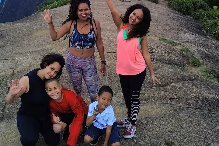Family poses with scenic backdrop on the Trail to Beautiful Stone in DA Tijuca Forest.