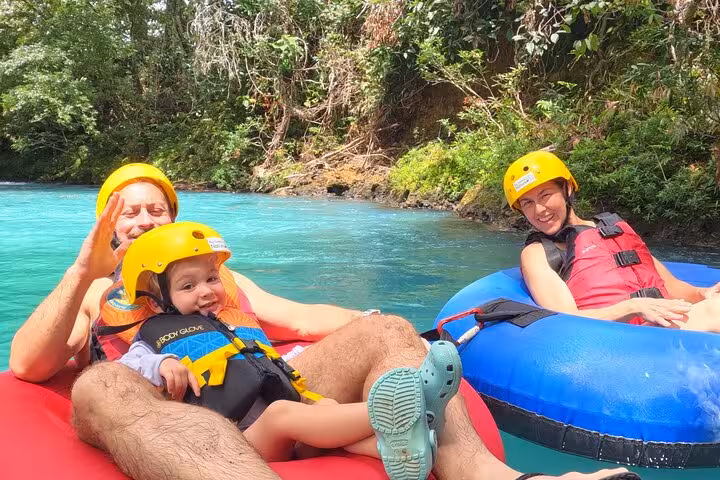 Happy family tubing on Rio Celeste, experiencing Costa Rica's natural beauty on a full-day hiking and tubing tour.