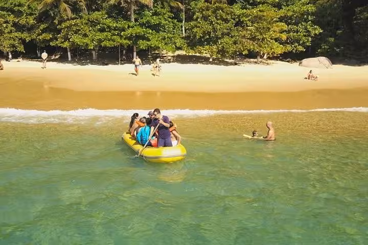 Family paddling in a yellow inflatable boat towards a golden sandy beach, a fun-filled adventure on the boat tour.