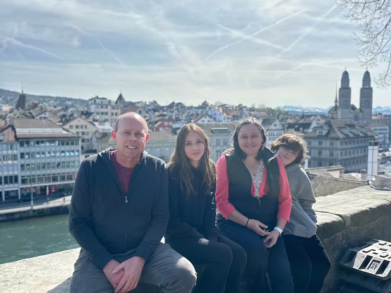 Family sitting on a wall overlooking Zurich's scenic skyline and historic architecture during a private tour.