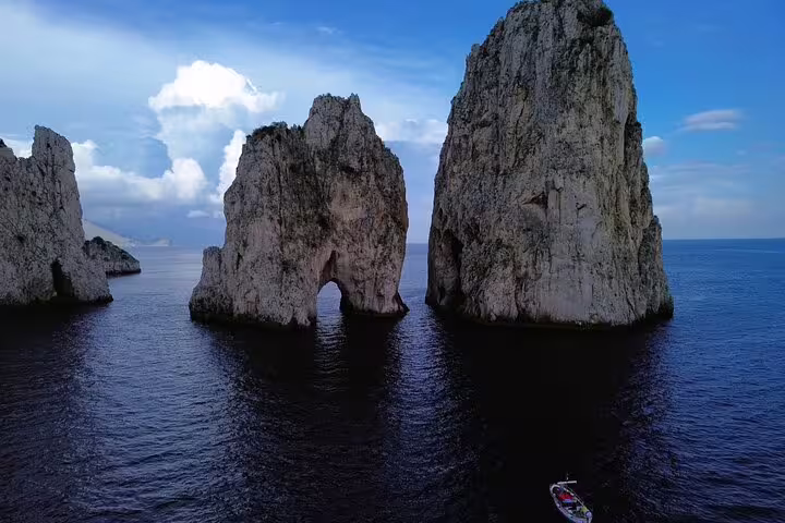 Faraglioni rocks on a private Capri boat tour, cruising past the iconic sea arch and dramatic limestone stacks