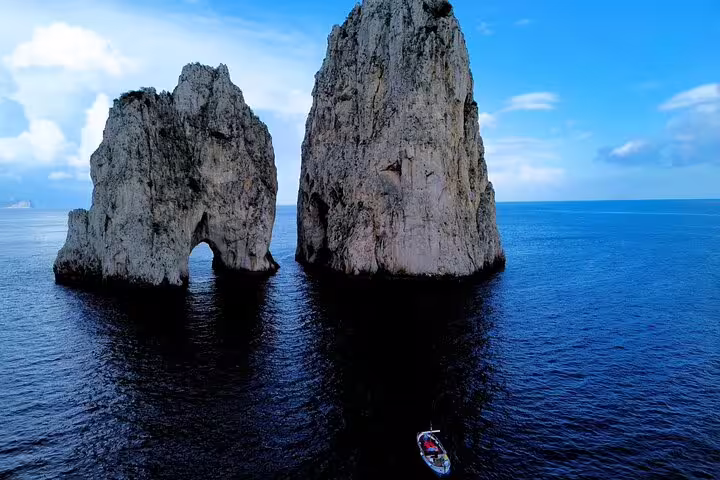 Faraglioni rocks seen on Capri 3-hour private classic Gozzo cruise, scenic boat tour over deep blue sea