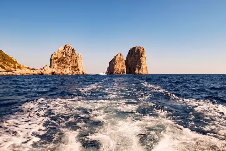 View of the iconic Faraglioni rocks from a small group boat tour around Capri Island, departing from Naples.