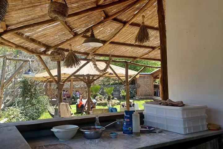 Rustic farm kitchen under a straw pergola set for cheese and pizza making with wine and limoncello tasting