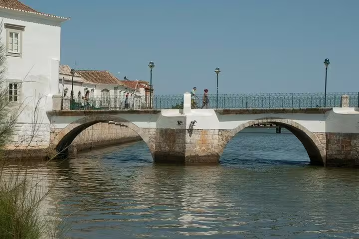 Historic arched bridge over calm lagoon waters on Algarve day trip from Faro to Vila Real de Santo António