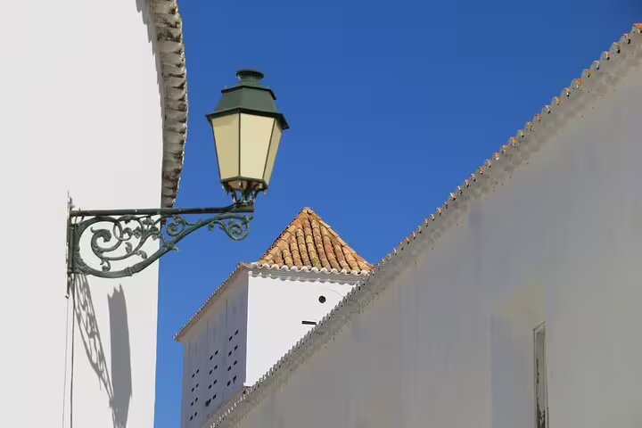 Historic Faro architecture with traditional whitewashed buildings and a vintage street lamp under a clear blue sky.