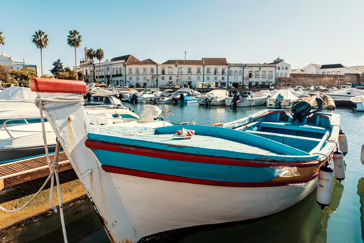 Colorful boat in Faro marina with historic waterfront buildings, Algarve day trip route to Vila Real de Santo António