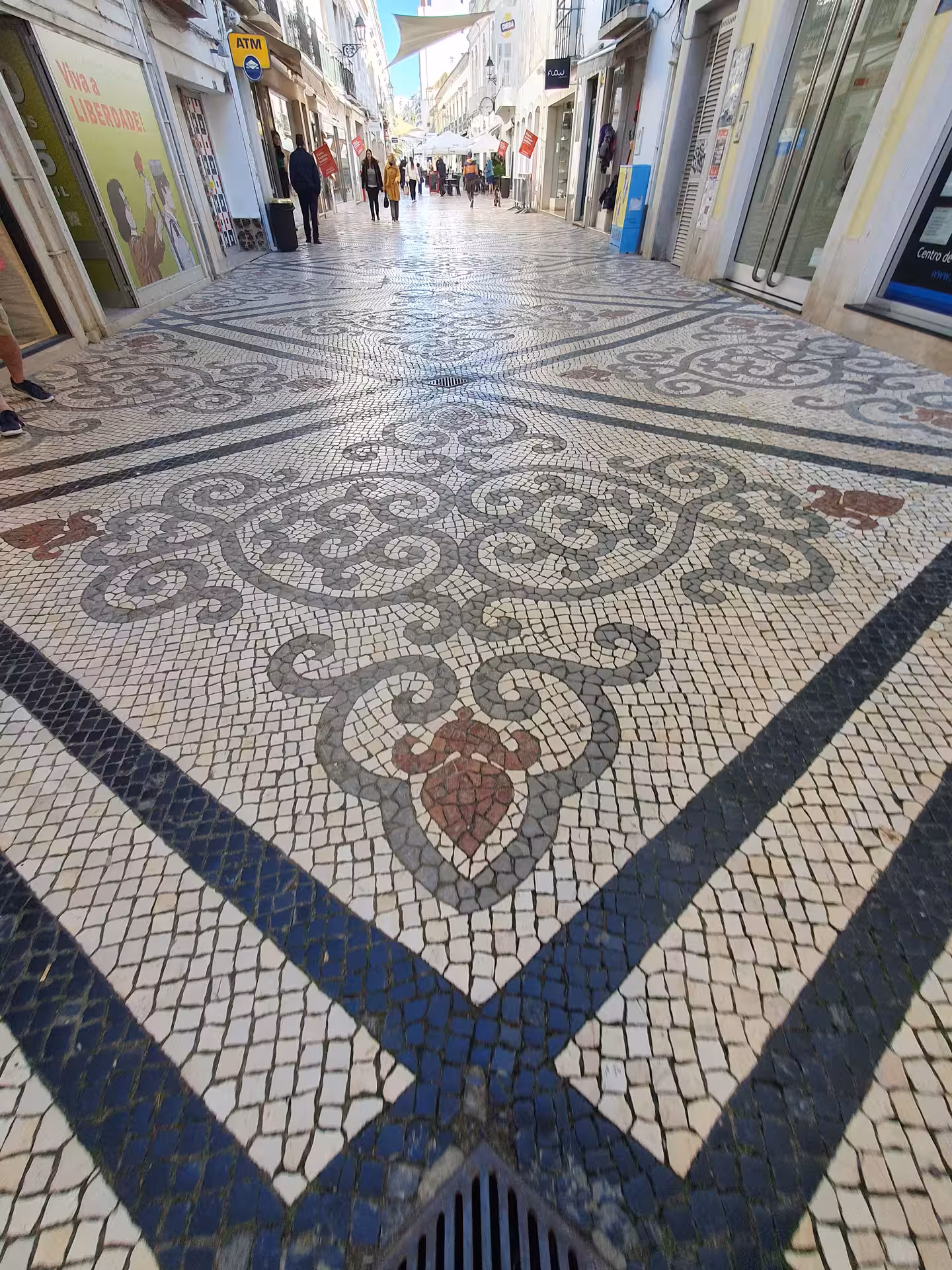 Intricate mosaic pavement on a bustling Faro street, showcasing Portuguese culture on an Algarve walking tour.