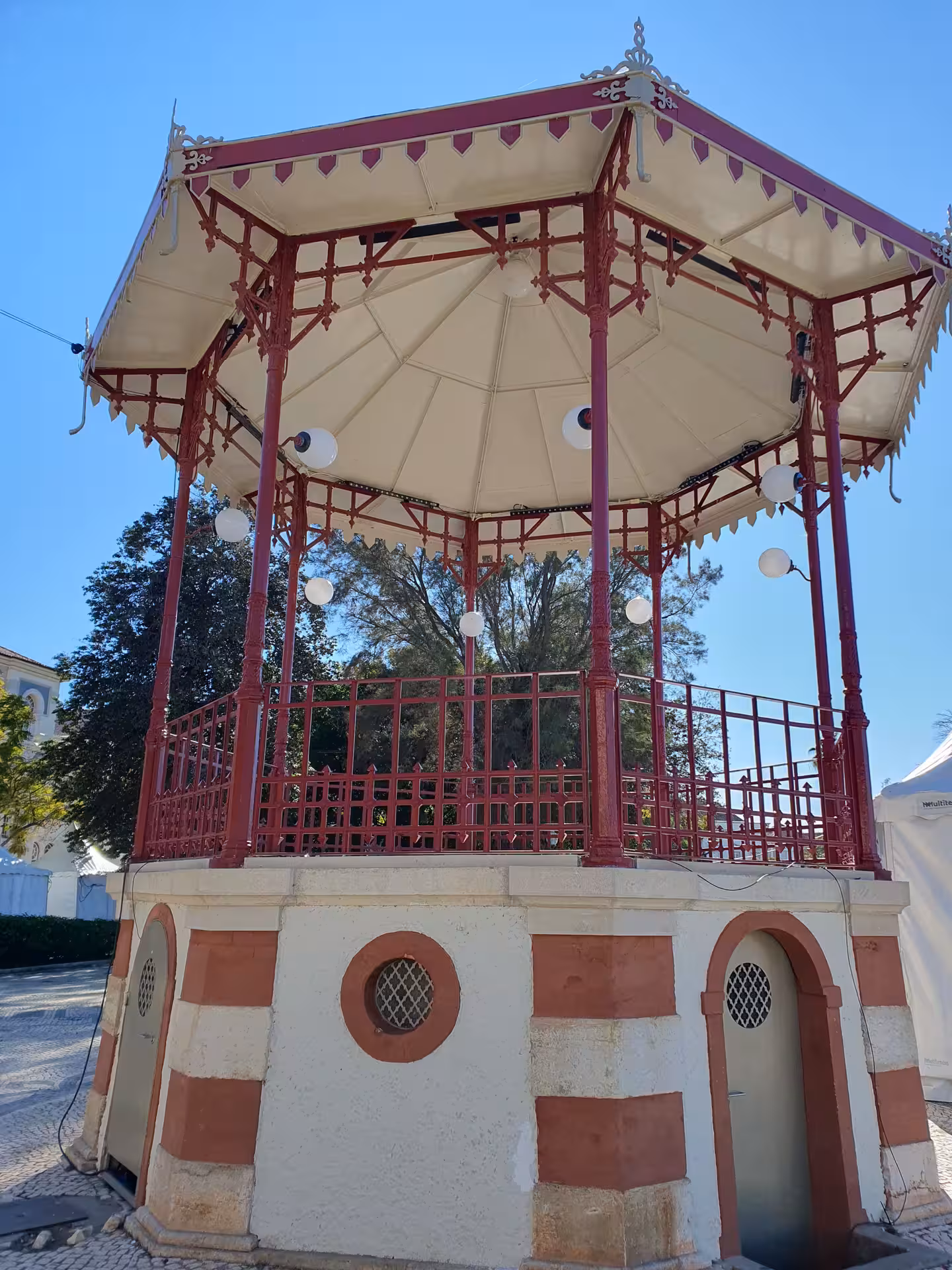 Ornate gazebo in Faro with intricate red and white design under blue sky, highlighting Algarve's architectural charm.