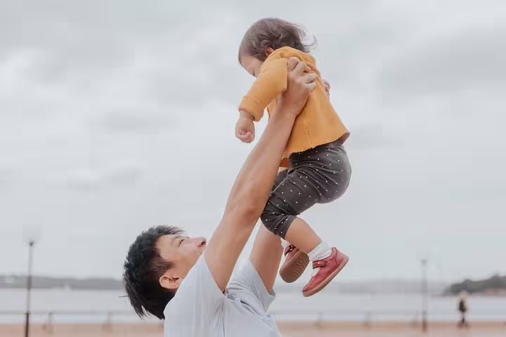 Father lifting child by the waterfront during a private Sydney travel photographer tour for candid family photos